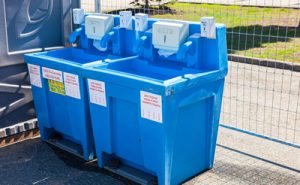 two blue hand washing stations near a fence